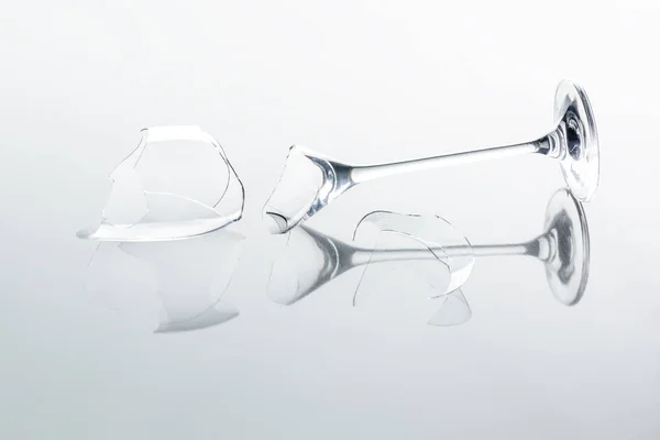 Broken wineglass on white reflecting tabletop — Stock Photo