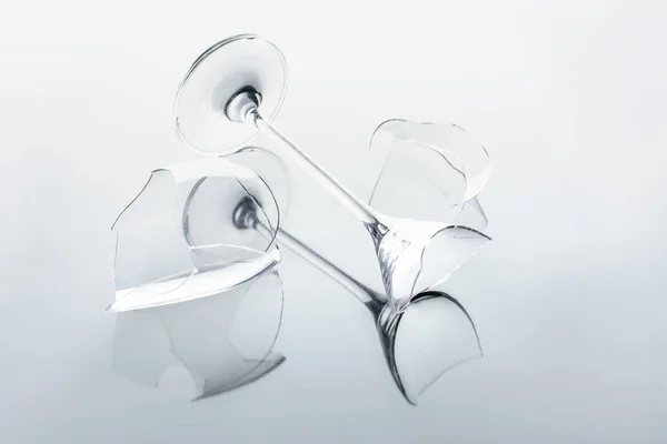 Broken wineglass on white reflecting surface — Stock Photo