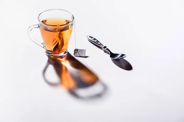 Tazza di vetro di tè nero e cucchiaio sul tavolo — Foto stock
