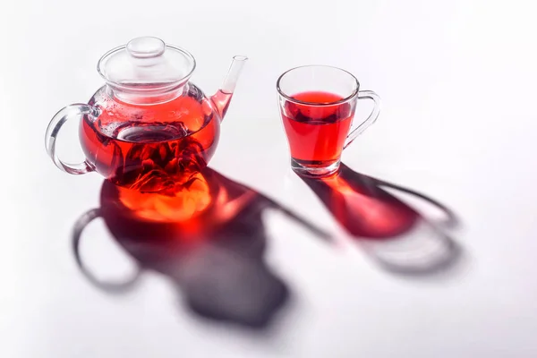 Glas Teekanne und Glas transparente Tasse mit Hibiskustee auf dem Tisch — Stockfoto