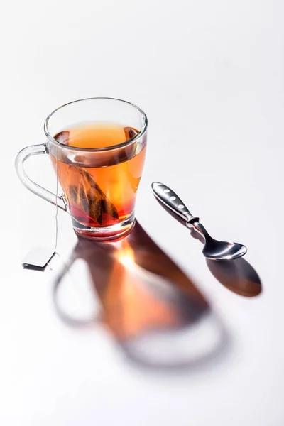 Tasse en verre de thé noir et cuillère sur la table — Photo de stock