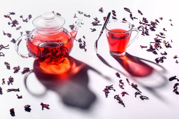 High angle view of glass teapot with hibiscus tea and cup with spoon on table — Stock Photo