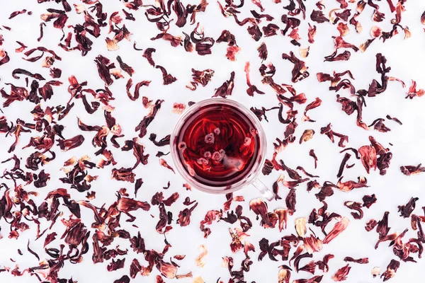 Vista superior da xícara com chá de hibisco entre chá espalhado isolado em branco — Fotografia de Stock