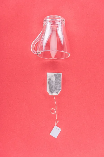 Top view of one tea bag and empty glass cup isolated on red — Stock Photo