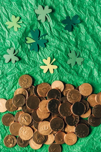 Vue du dessus des pièces d'or et du trèfle en papier sur la surface verte, concept de jour st patricks — Photo de stock