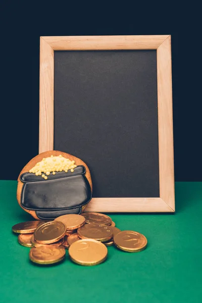 Leere Tafel mit Goldmünzen und Lebkuchen auf grünem Tisch, st patricks day concept — Stockfoto