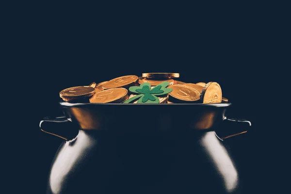 Black pot with golden coins isolated on black, st patricks day concept — Stock Photo