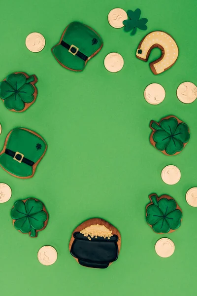 Vista superior de galletas de hielo y monedas de oro aisladas en verde, st patricks concepto de día - foto de stock
