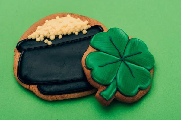 Vista ad alto angolo di biscotti glassa a forma di pentola con monete e trifoglio su verde, concetto giorno st patricks — Foto stock