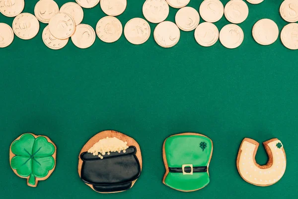 Верхний вид глазури печенье и золотые монеты изолированы на зеленый, День святого Патрика концепции — стоковое фото