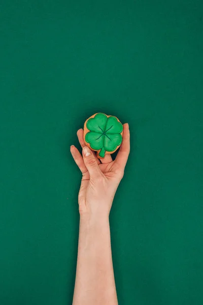 Abgeschnittenes Bild einer Frau mit Keks in Form von Shamrock isoliert auf grünem, st patricks day concept — Stockfoto