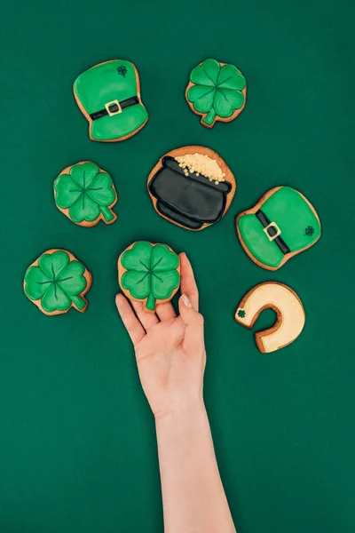 Immagine ritagliata di donna in possesso di biscotti glassa isolato su verde, st patricks concetto giorno — Foto stock