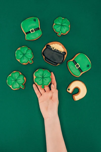 Imagen recortada de la mujer sosteniendo galletas de hielo aisladas en verde, st patricks concepto de día - foto de stock