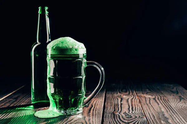 Verre et bouteille de bière verte sur table en bois, concept de jour st patricks — Photo de stock