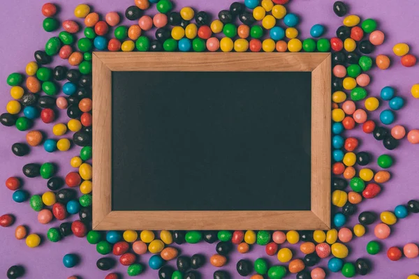 Top view of candies and empty blackboard isolated on purple — Stock Photo