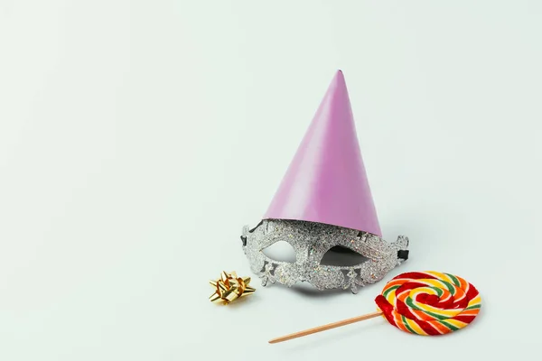 Vue rapprochée du masque de mascarade, du cône de fête et de la sucette isolés sur gris — Photo de stock