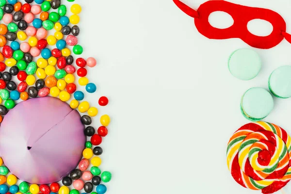 Vue de dessus du cône de fête arrangé, masque de mascarade, macarons et bonbons isolés sur gris — Photo de stock