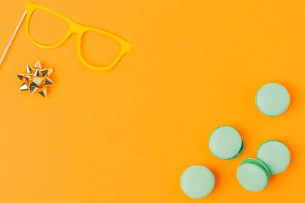 Top view of party mask, bow and macarons isolated on orange, purim holiday concept — Stock Photo