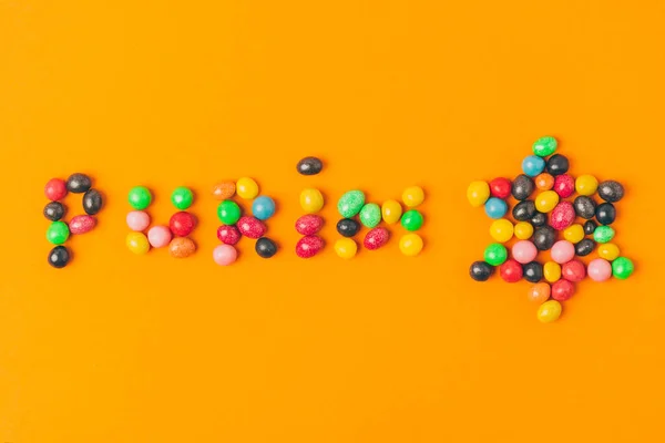 Vista dall'alto di lettering purim fatta di caramelle e stella isolata su arancione — Foto stock