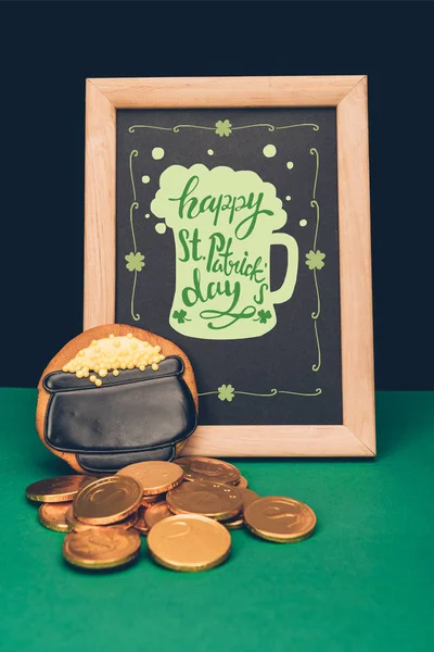 Close up view of festive cookie, golden coins and blackboard with happy st patricks day lettering, st patricks day holiday concept — Stock Photo