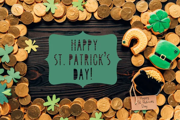 Flat lay with golden coins, festive cookies and happy st patricks day lettering on wooden surface — Stock Photo