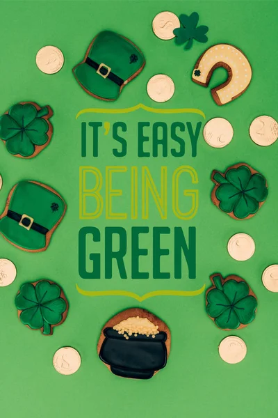 Tendido plano con galletas festivas y su fácil ser letras verdes aisladas en verde - foto de stock