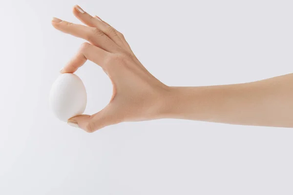 Cropped image of hand holding egg on white background — Stock Photo