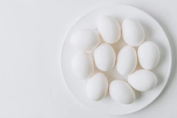 Uova bianche che depongono su piastra bianca su sfondo bianco — Foto stock