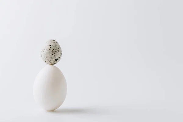 White egg and quail egg stacked on white background — Stock Photo