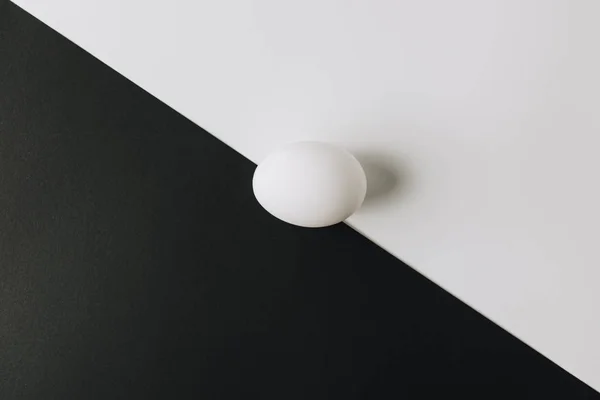 White egg laying in middle of black and white background — Stock Photo