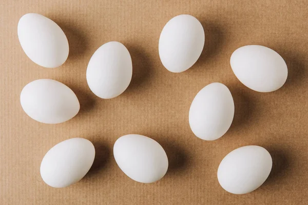 White eggs scattered on brown carton — Stock Photo