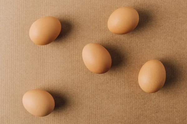 Huevos marrones esparcidos en cartón marrón - foto de stock