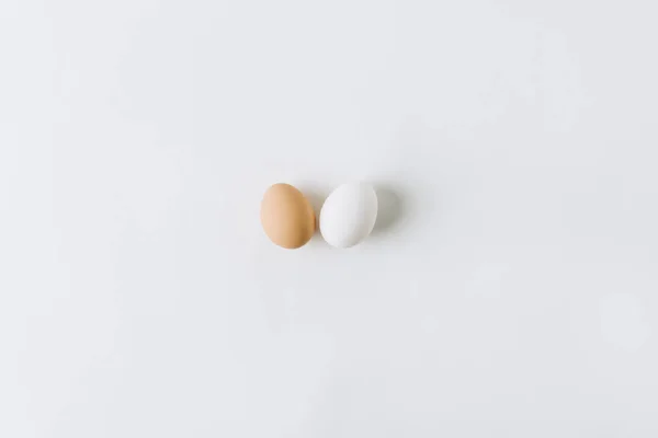 Белые и коричневые яйца откладывают на белом фоне — стоковое фото