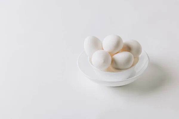 Œufs blancs pondus sur plaque blanche sur fond blanc — Photo de stock