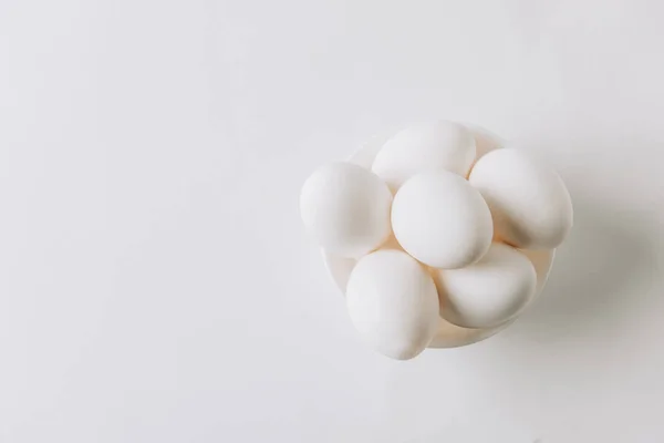 Ansicht von weißen Eiern, die auf weißem Teller auf weißem Hintergrund liegen — Stockfoto