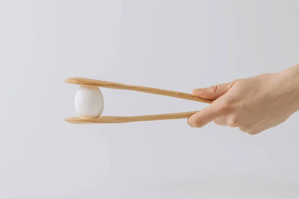 Обрізане зображення руки, що тримає дерев'яні щиколотки з білим яйцем — стокове фото