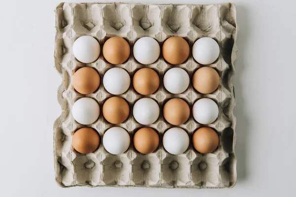 Œufs blancs et bruns pondant dans un carton d'œufs sur fond blanc — Photo de stock