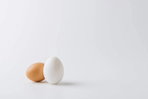 Un huevo blanco y uno marrón que ponen sobre fondo blanco — Stock Photo