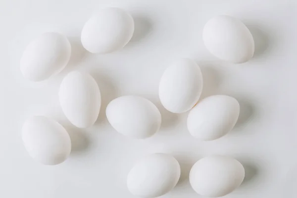 Oeufs blancs éparpillés sur fond blanc — Photo de stock