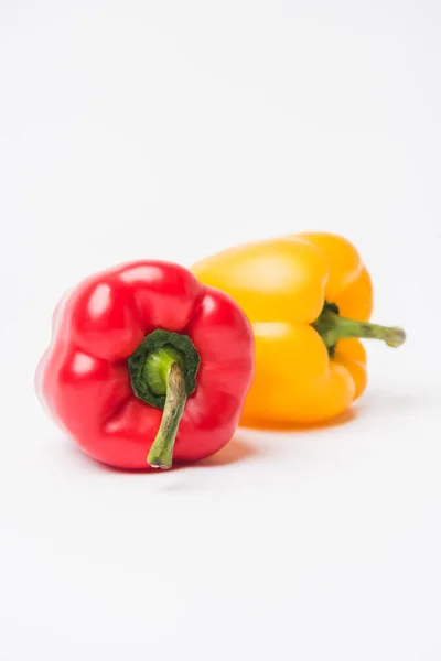 Red and yellow bell peppers laying on white background — Stock Photo