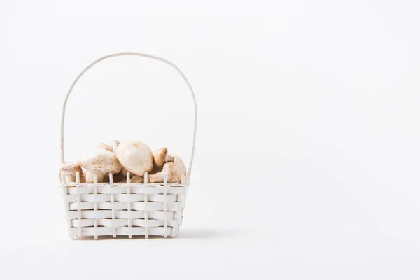 Heap of champignon mushrooms laying in wicker basket on white background — Stock Photo