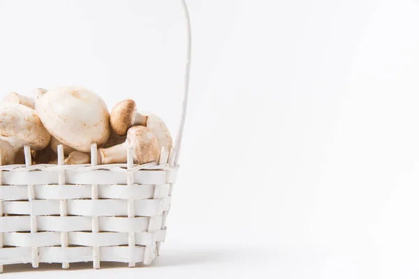 Heap of mushrooms laying in wicker basket on white background — Stock Photo