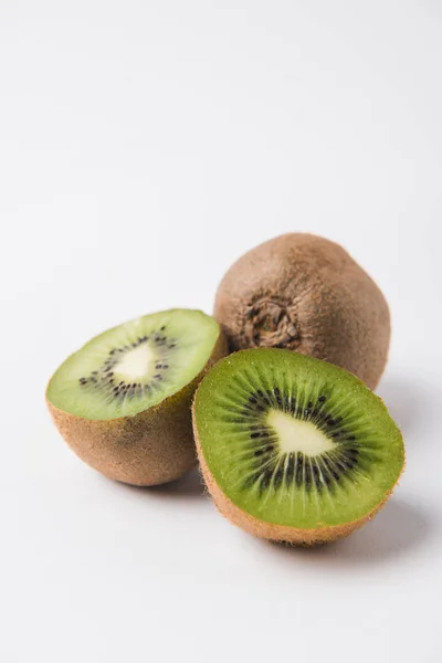 Kiwi entero y reducido a la mitad sobre fondo blanco - foto de stock