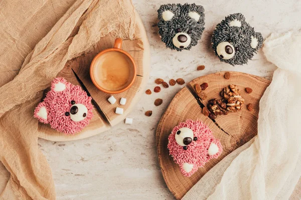 Vista superior de deliciosas magdalenas en forma de osos con taza de café en la mesa - foto de stock