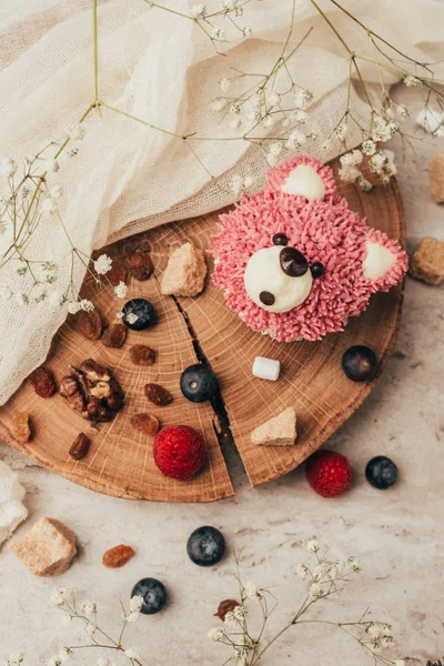 Draufsicht auf köstlichen Muffin in Bärenform mit Beeren auf Holzbrett — Stockfoto