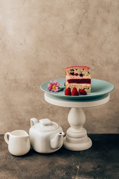 Pastel sabroso dulce con frambuesas y flor y hervidor de agua con jarra de porcelana - foto de stock