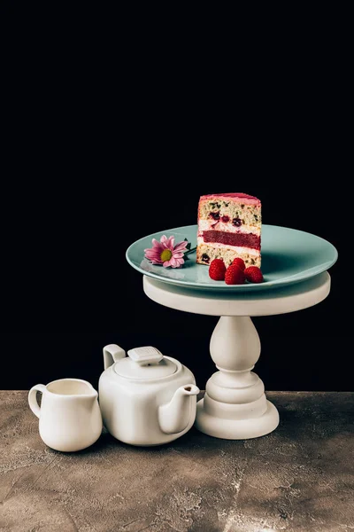 Delicious cake with raspberries and flower and kettle with porcelain jug on black — Stock Photo