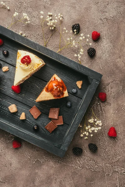 Vista superior de dulces pasteles sabrosos con chocolate y bayas en bandeja de madera — Stock Photo