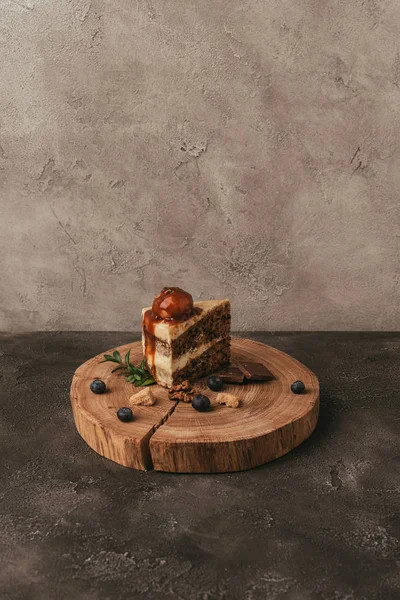 Doce saboroso pedaço de bolo com chocolate e mirtilos na tábua de madeira — Fotografia de Stock