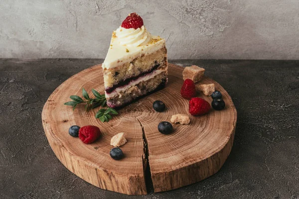 Vista ravvicinata di dolce torta saporita con panna montata e bacche su tavola di legno — Foto stock